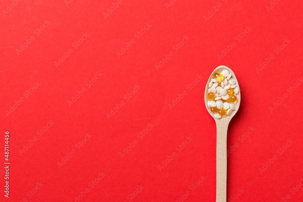 Vitamin capsules in a wooden spoon on a colored background. Pills served as a healthy meal. Drugs, pharmacy, medicine or medical healthycare concept Vitamin capsules in a wooden spoon on a colored background. Pills served as a healthy meal. Drugs, pharmacy, medicine or medical healthycare concept