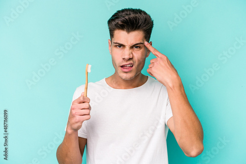 Young caucasian man brushing teeth isolated on white background showing a disappointment gesture with forefinger.