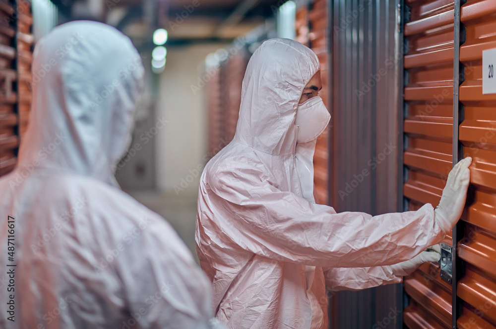 Two people in hazmat suits standing in the storehouse Two people in hazmat suits standing in the storehouse