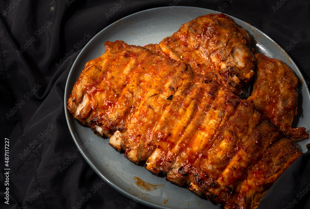 Baked pork ribs in a plate. on a dark background