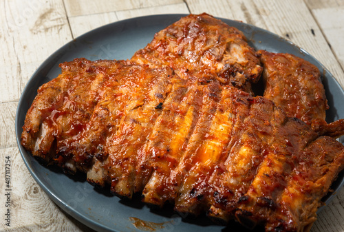 Baked pork ribs in a plate. on a dark background