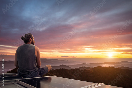 Man watching a beautiful sunset from the roof of a camper van photo