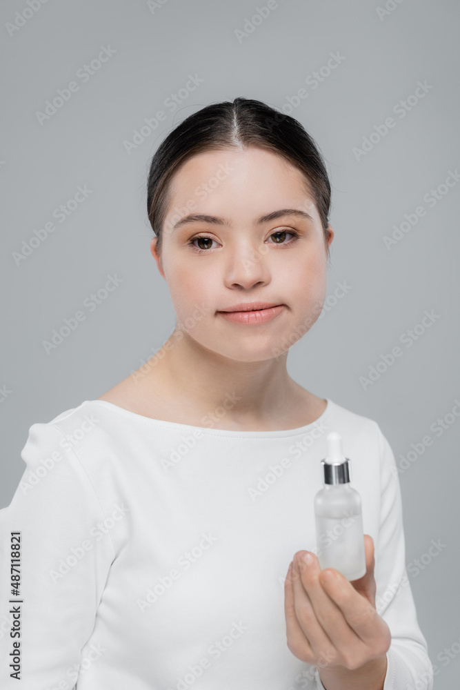 Young woman with down syndrome holding serum isolated on grey Young woman with down syndrome holding serum isolated on grey