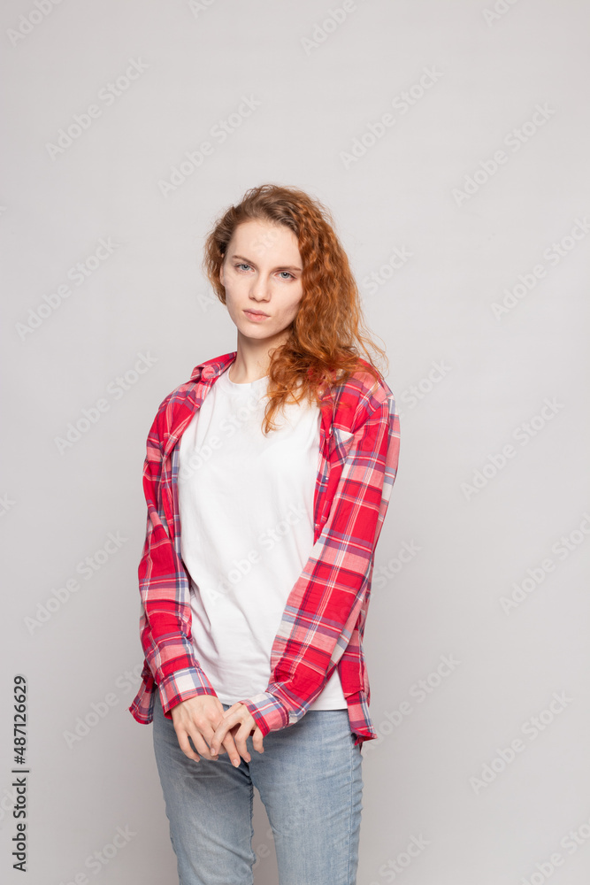 a young girl in a plaid shirt stands sad against a light background a young girl in a plaid shirt stands sad against a light background