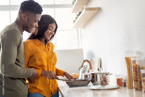 Happy Young Black Couple Cooking Food On A Stove In Kitchen