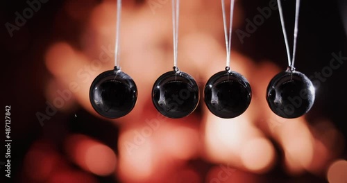 Balls in Newton's pendulum hit the background of fire. Slow-motion video