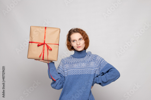 young girl in a sweater is holding a gift on a white background
