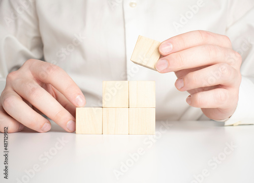 Hand putting and stacking blank wooden cubes on table with copy space for input wording and infographic icon.