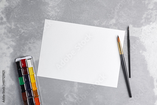 Blank paper mockup for watercolor drawing, artwork or illustration. White paper sheet with paintbrush and watercolor palette photo