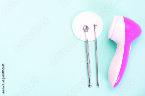 uno scoop and facial massager are on a soft turquoise background. flat lay  cosmetology