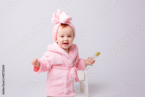 Cute little baby girl in pink terry with makeup isolated on a white background, repeats the behavior of mom
