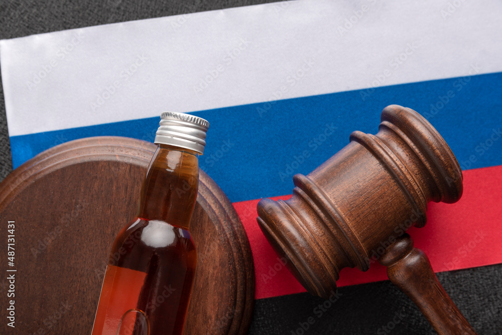Judge gavel and bottle of alcohol on flag of Russia background. Law on alcohol in Russia. Concept alcohol and conflicts with the law.
