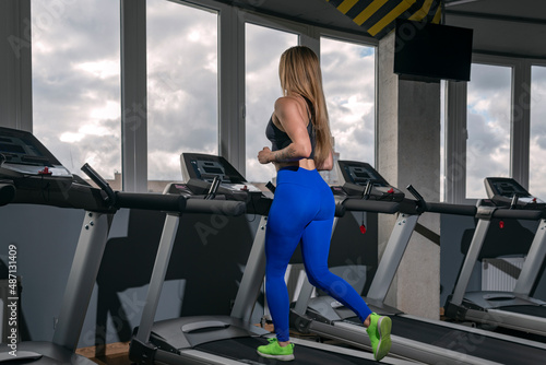 Young fitness girl is engaged in cardio training in the modern gym. Woman doing cardio training on treadmill.