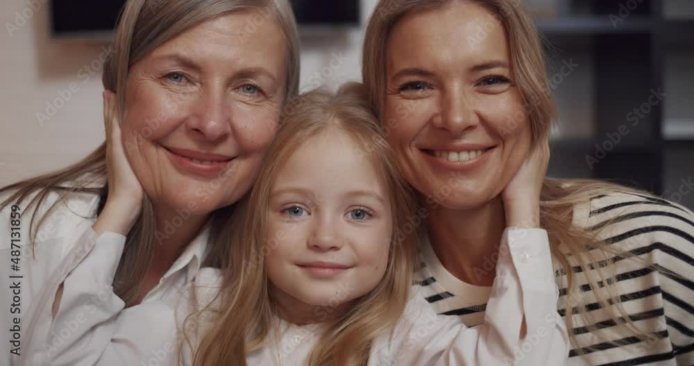 Family Portrait of Smiling Little Girl with Mother and Elderly Grandmother. Three Generations of Relatives Beautiful Women posing, hugging looking into camera. Grandkid between Mother and Granny. Family Portrait of Smiling Little Girl with Mother and Elderly Grandmother. Three Generations of Relatives Beautiful Women posing, hugging looking into camera. Grandkid between Mother and Granny.