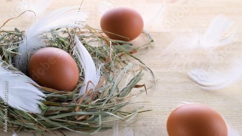Easter eggs basket. Natural colour egg in basket with spring tulips, white feathers on wooden table background in Happy Easter decoration. Traditional decoration in sun light