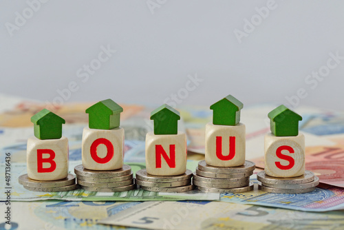 Foto Wooden house and blocks with the word Bonus on coins and banknotes - Concept of