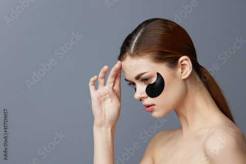 young woman eye patches on face bare shoulders skin care isolated background