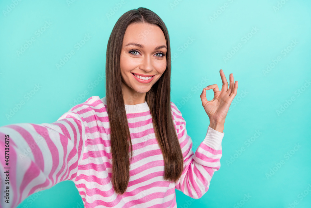 Self-portrait of attractive cheerful cute nice confident girl showing ok-sign advert ad isolated over bright teal turquoise color background Self-portrait of attractive cheerful cute nice confident girl showing ok-sign advert ad isolated over bright teal turquoise color background