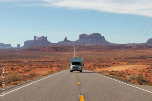 Motorhome roadtripping with Monument Valley behind under blue sky