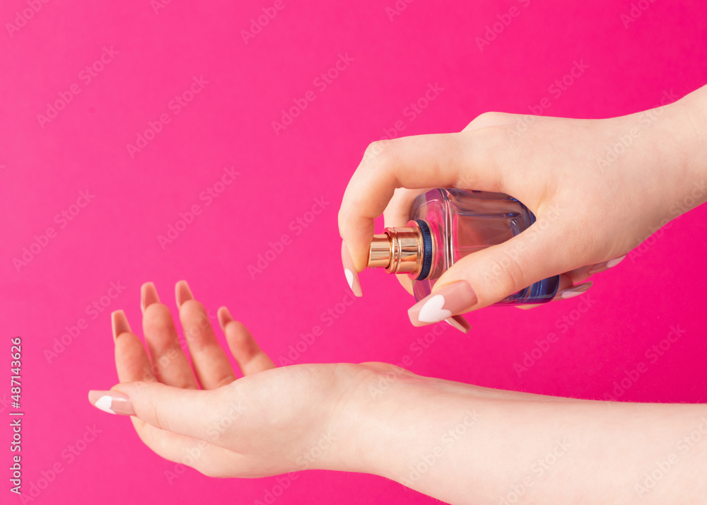 female hands with perfume bottle on pink background female hands with perfume bottle on pink background
