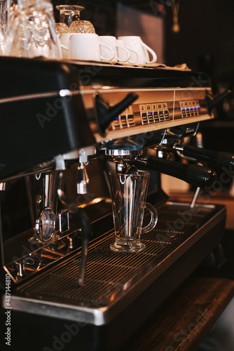 Glass beaker for making espresso in a coffee machine. Barista prepares cappuccino. Preparation of aromatic coffee in the morning