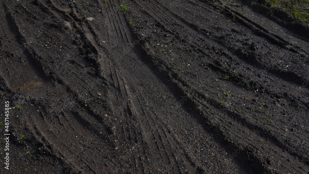 Naklejka premium Muddy field with tire tracks and puddles. Dirty road with mud truck wheel tracks after rain. Off-road.