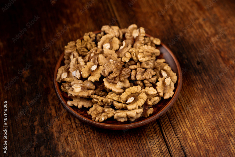 Peeled walnuts on a plate. Dark wooden background. Vegetarian, healthy food. Peeled walnuts on a plate. Dark wooden background. Vegetarian, healthy food.