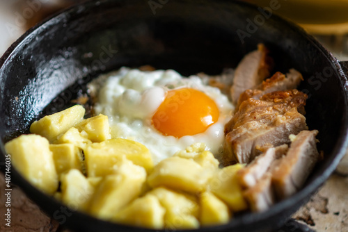 Fried eggs, potatoes and meat in a frying pan. Breakfast preparation.