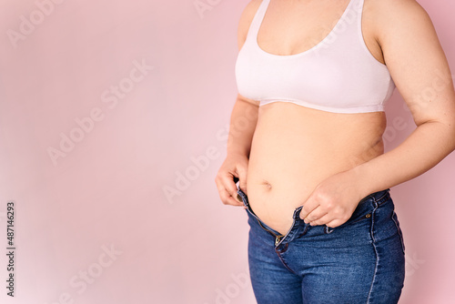 The concept of the diet is a close-up of women's hands that cannot fasten their trousers due to an increase in fat on the hips after childbirth. a girl during breastfeeding. recovery. space for text.