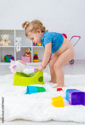 The child sits on a potty with a toy. Selective focus.