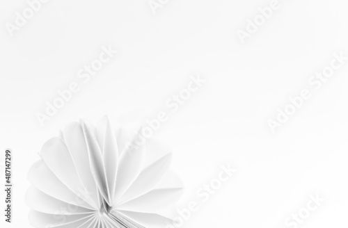 Białe tło z półokrągłą papierową dekoracją przypominającą kwiat, fantazyjny wzór.