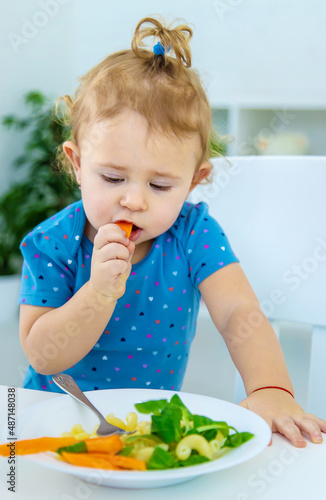 Child baby eats pasta with vegetables. Selective focus.