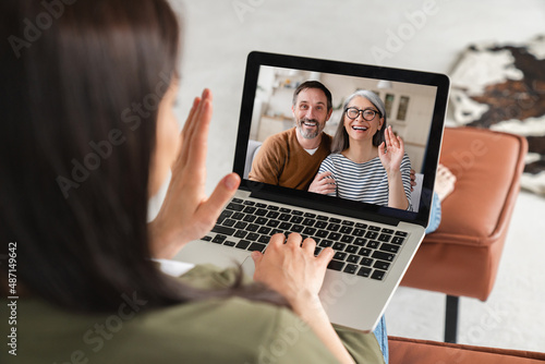 Daughter talking remotely on distance with senior old elderly grandparents parents on video call conference conversation online on laptop screen. Back view portrait. Family on lockdown.