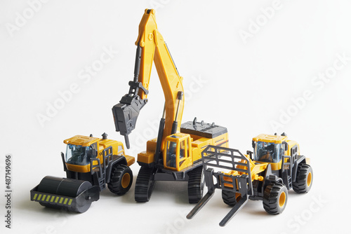 Set of toy construction equipment: asphalt paver, hydraulic hammer and loader on a white background. Concept of machines for construction and landscaping work. Free space for an inscription
