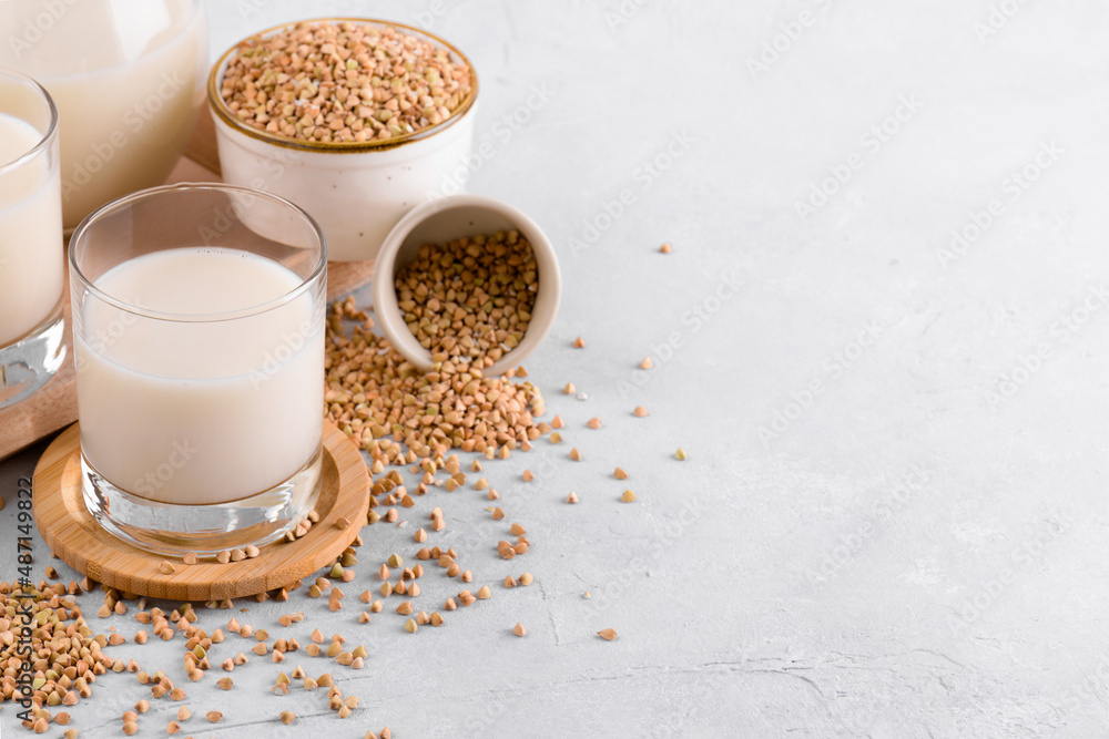 Vegan non diary buckwheat milk in glasses with buckwheat groats in a bowl on white stone table. Vegan buckwheat drink is plant based alternative milk . Veggies healthy milk product, copy space Vegan non diary buckwheat milk in glasses with buckwheat groats in a bowl on white stone table. Vegan buckwheat drink is plant based alternative milk . Veggies healthy milk product, copy space