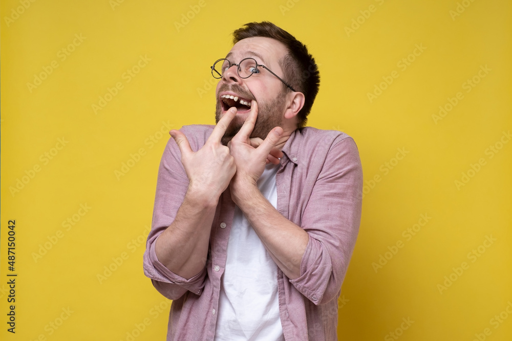 Man in glasses and casual clothes opened his mouth and shows a missing tooth with fingers. Man in glasses and casual clothes opened his mouth and shows a missing tooth with fingers.