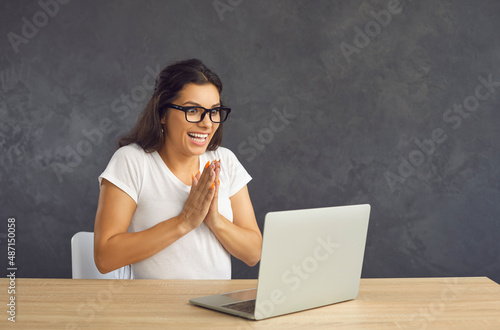 Excited young Caucasian woman in glasses sit on desk triumph with online lottery win on laptop. Overjoyed millennial female in spectacles feel euphoric with promotion or sale discount on computer.