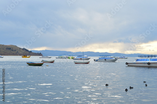Landscape with boats on lake and cloudy sky in late afternoon © Thamirys Ferraz