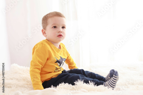 Three-year-old child sitting in bed in a white room