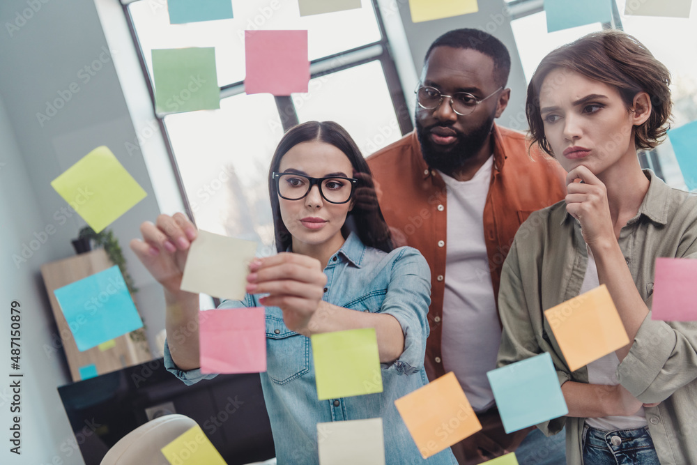 Portrait of attractive focused clever intelligent group brainstorming putting memo sticks on glass in office workplace workstation indoors Portrait of attractive focused clever intelligent group brainstorming putting memo sticks on glass in office workplace workstation indoors