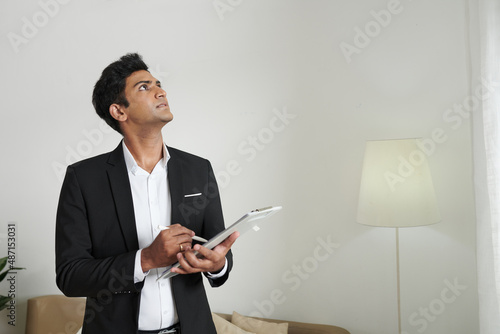 Billede på lærred Property insurance agent inspecting apartment of client and taking notes in docu