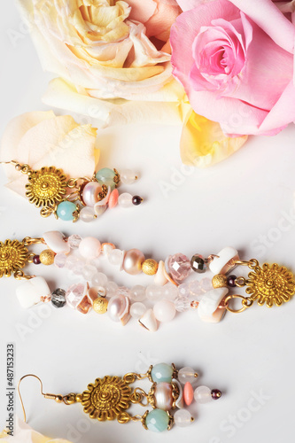 golden  jewerly bracelet and earning with semiprecious and roses petals at white background