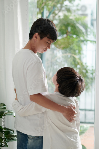 Boy hugging his father and asking him question, view from the back