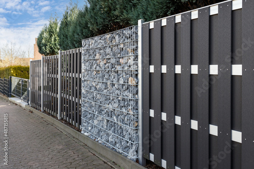 Modern gabion wall system with stones as element of garden or house wooden metal fence. photo