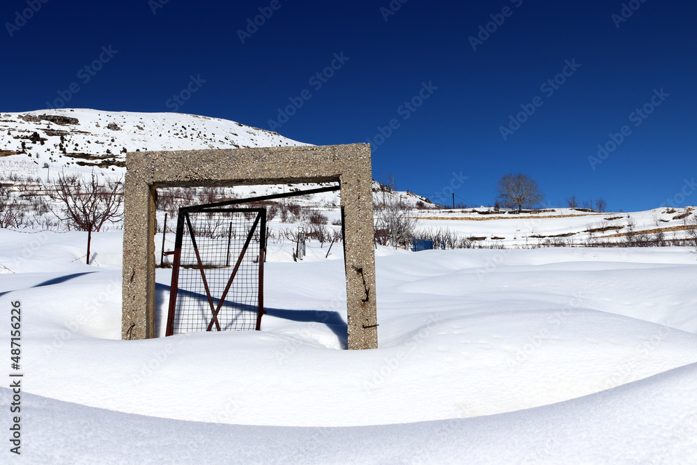 Single damaged door in an empty field covered with snow Single damaged door in an empty field covered with snow