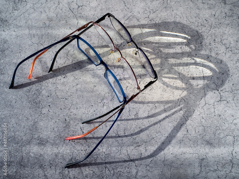 The eyeglasses are placed next to each other. The shadow from the glasses and the light passing through the lenses are visible on the table surface. Background with glasses to improve vision. The eyeglasses are placed next to each other. The shadow from the glasses and the light passing through the lenses are visible on the table surface. Background with glasses to improve vision.