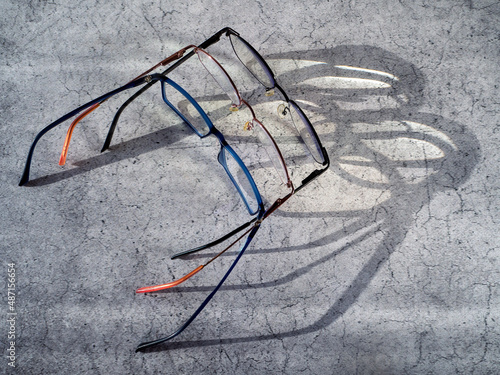 The eyeglasses are placed next to each other. The shadow from the glasses and the light passing through the lenses are visible on the table surface. Background with glasses to improve vision. photo
