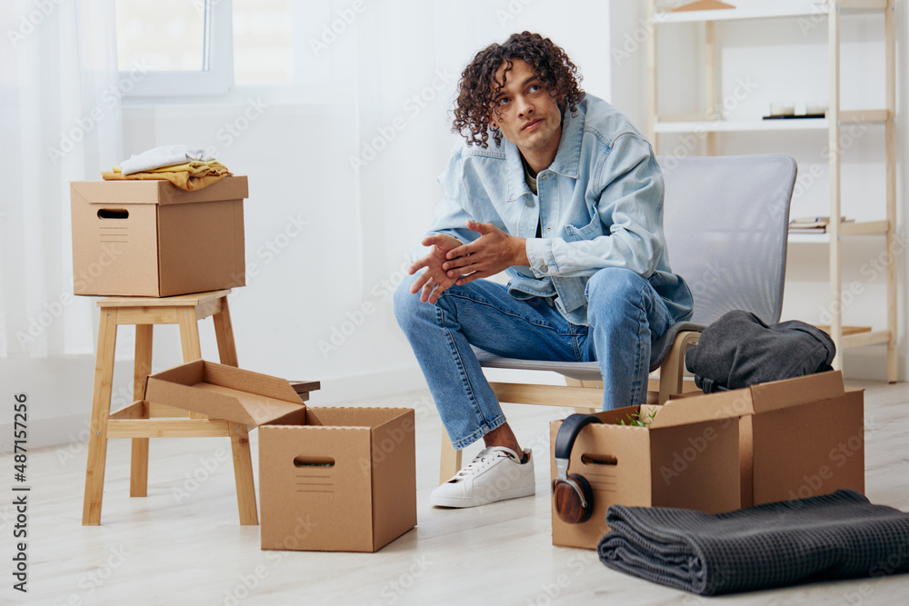 handsome guy sitting on a chair with boxes interior moving interior handsome guy sitting on a chair with boxes interior moving interior