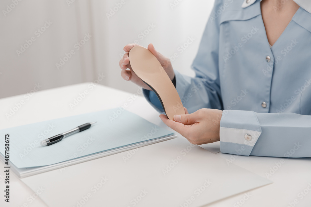 Doctor holding an insole while sitting at a table. Orthopedist tests