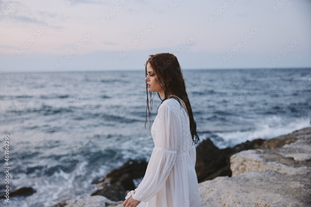 woman looking into the distance standing on the rocks landscape ocean travel woman looking into the distance standing on the rocks landscape ocean travel